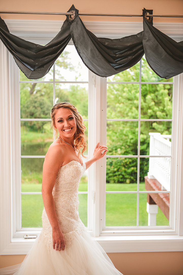 a bride laughing as she stand by a window in Oak Forest