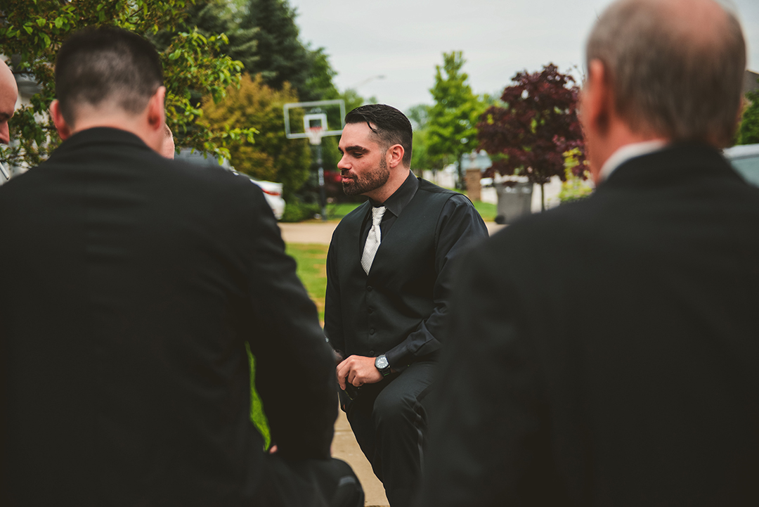 the groom hanging out with his groomsmen in his driveway