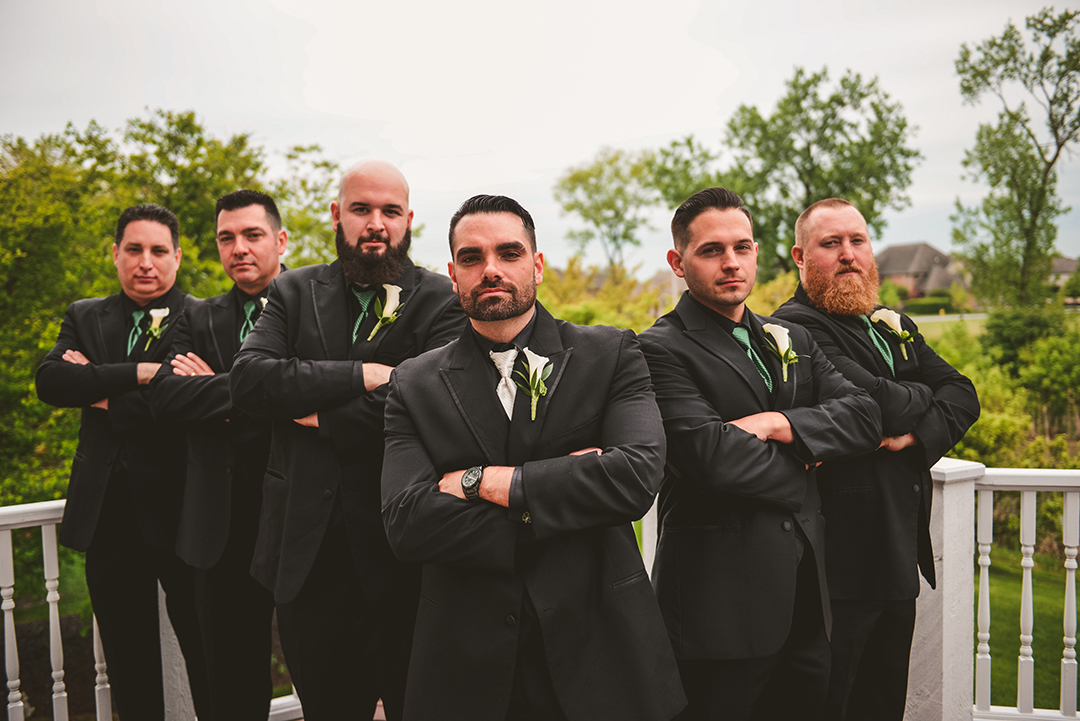 tough looking groomsmen standing out on a deck with their arms crossed