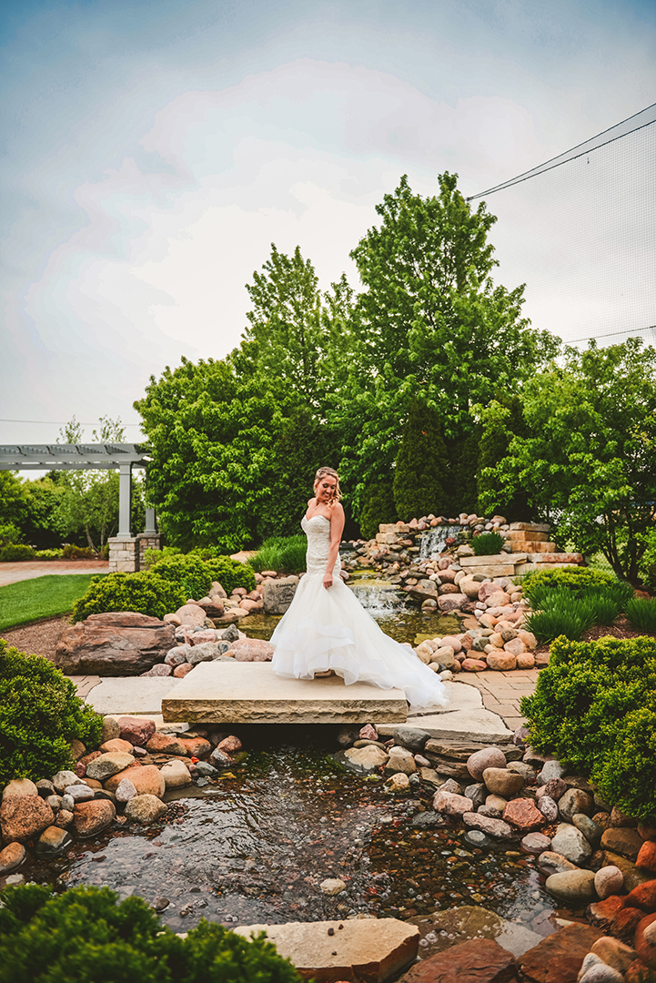 a gorgeous bride standing in front of a waterfall with her train flowing behind her