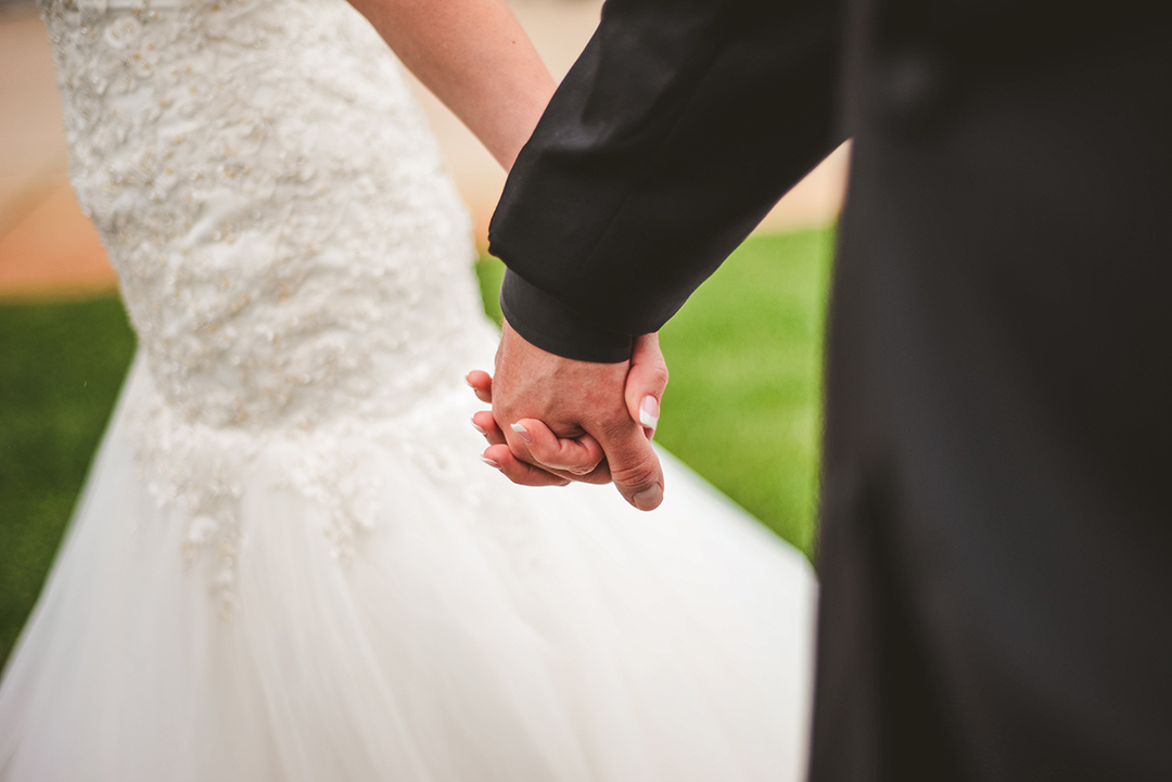 a detail of a bride and groom holding hands