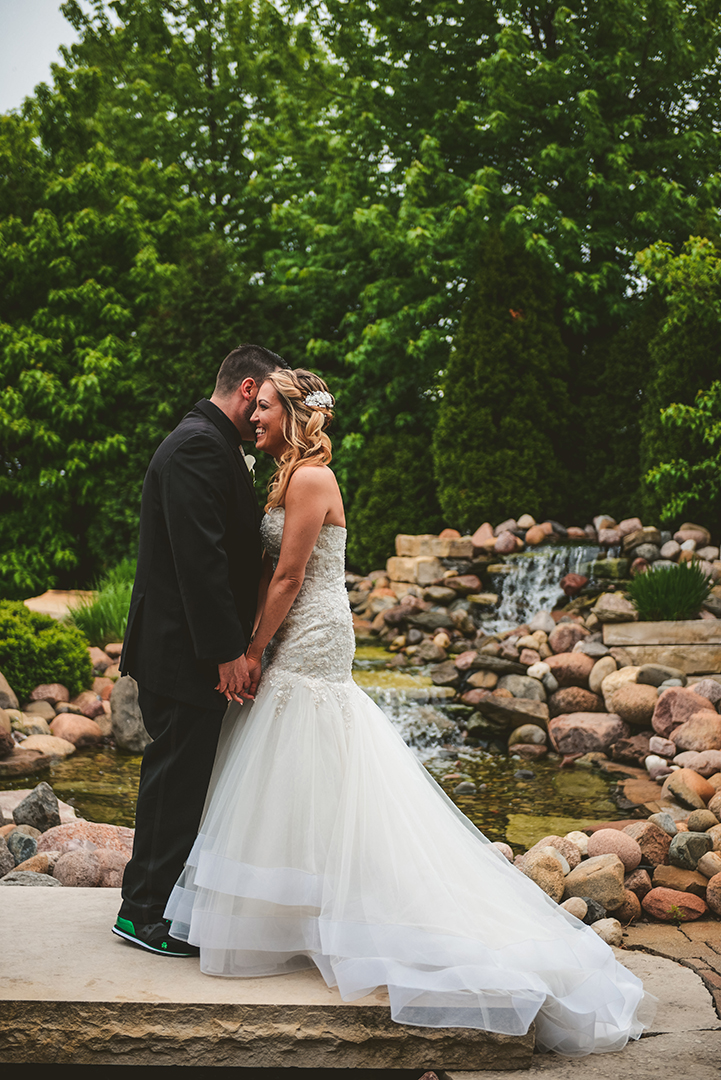 a groom whispering into his brides ear as they hold hands