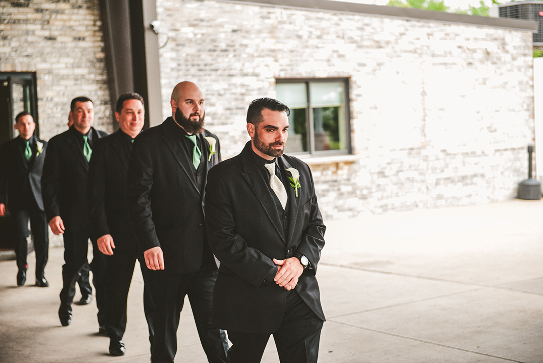 the groom walking down the aisle with his groomsmen right behind him