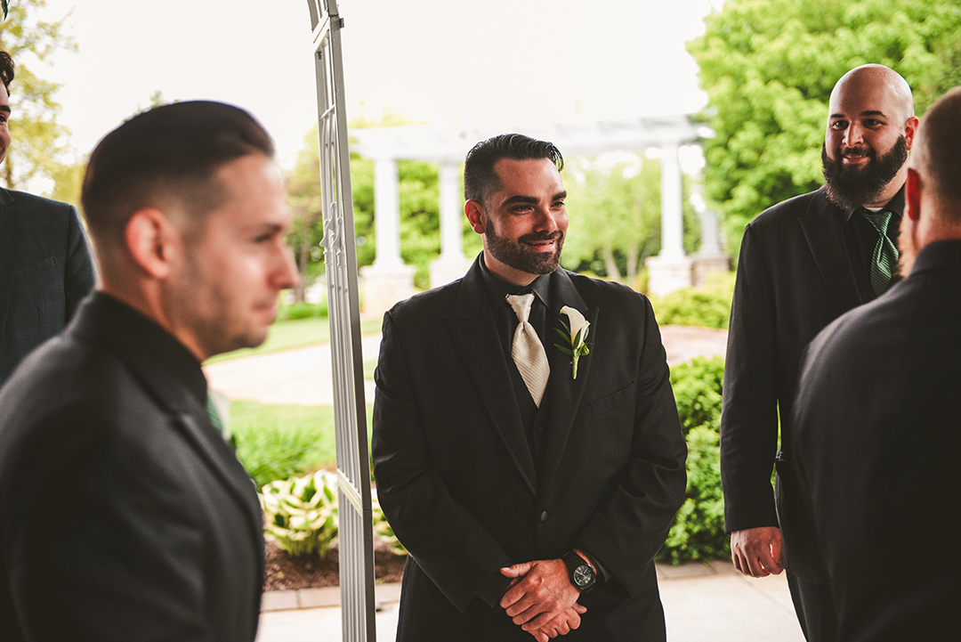 the groom smiling as his bride comes down the aisle