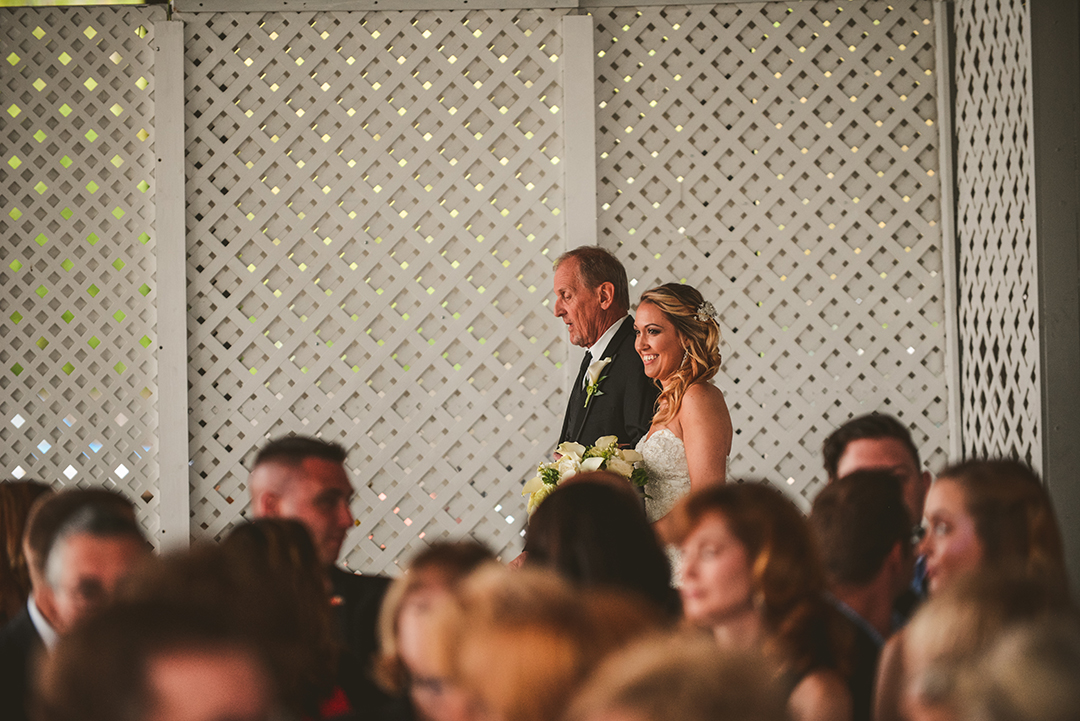 a bride and her father linking arms as they come down the aisle