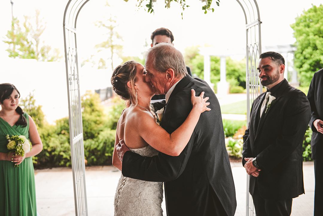 a father kissing his daughter as he hands her off on her wedding day