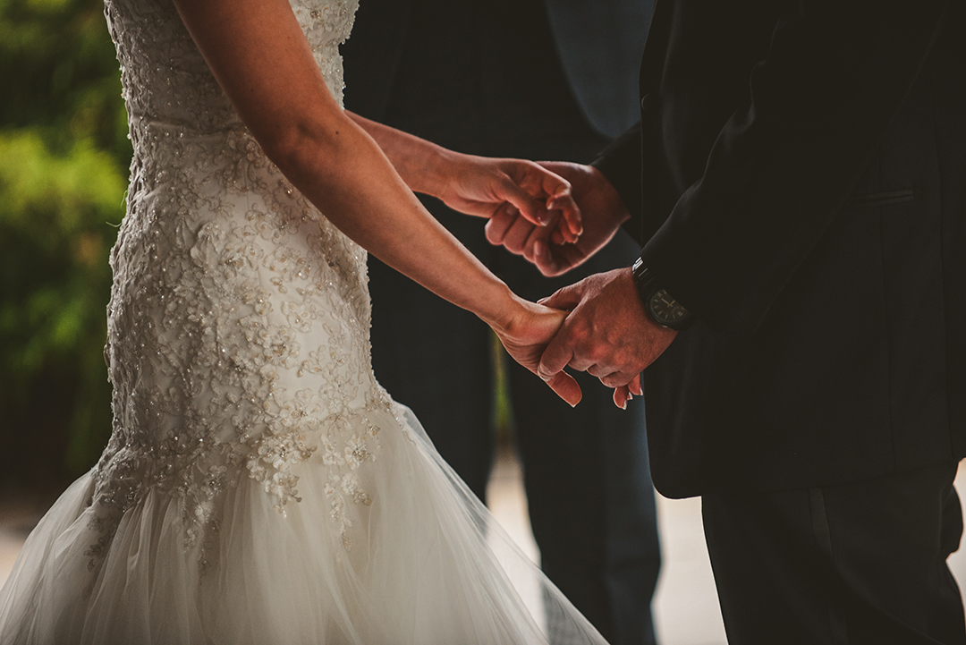 the bride and groom holding hands during their wedding ceremony