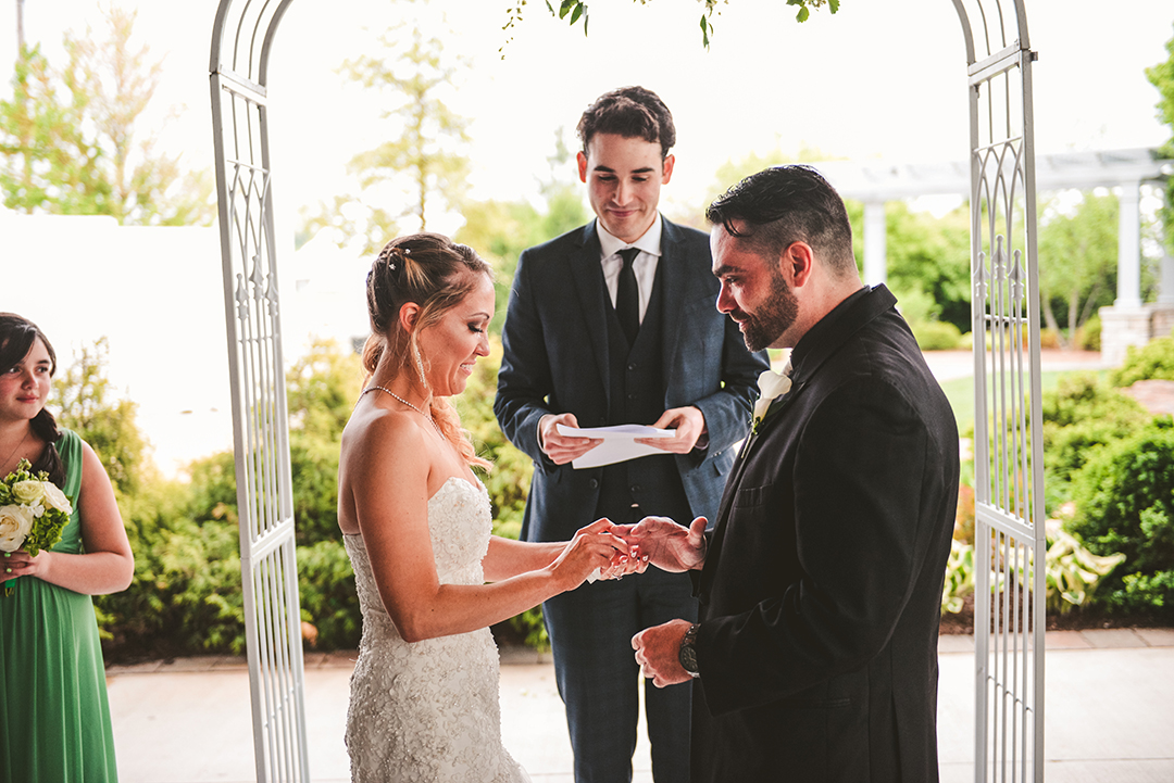 the bride putting on her husbands ring during their wedding