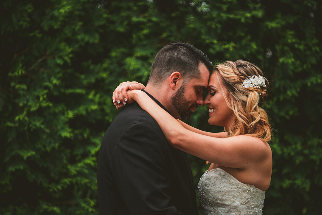 the bride and groom getting close as the bride throws her arm around him