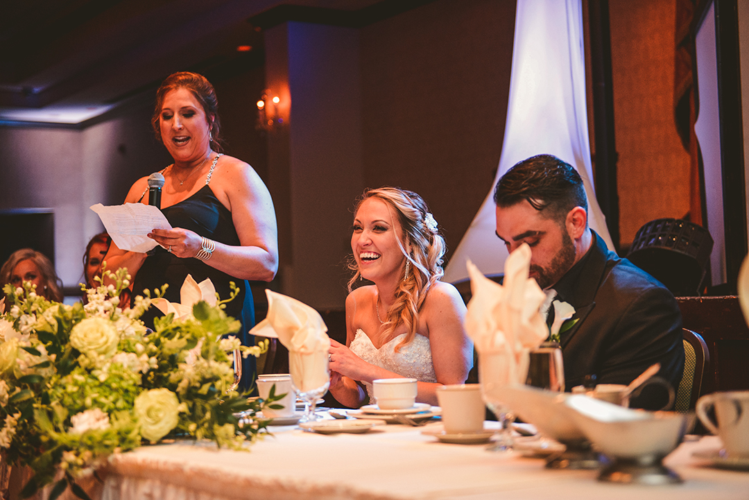 the bride laughing while her sister gives a speech