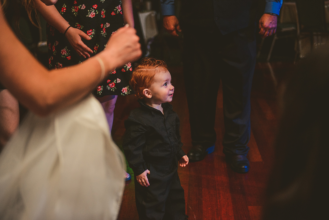 the bride and grooms son watching guests dance