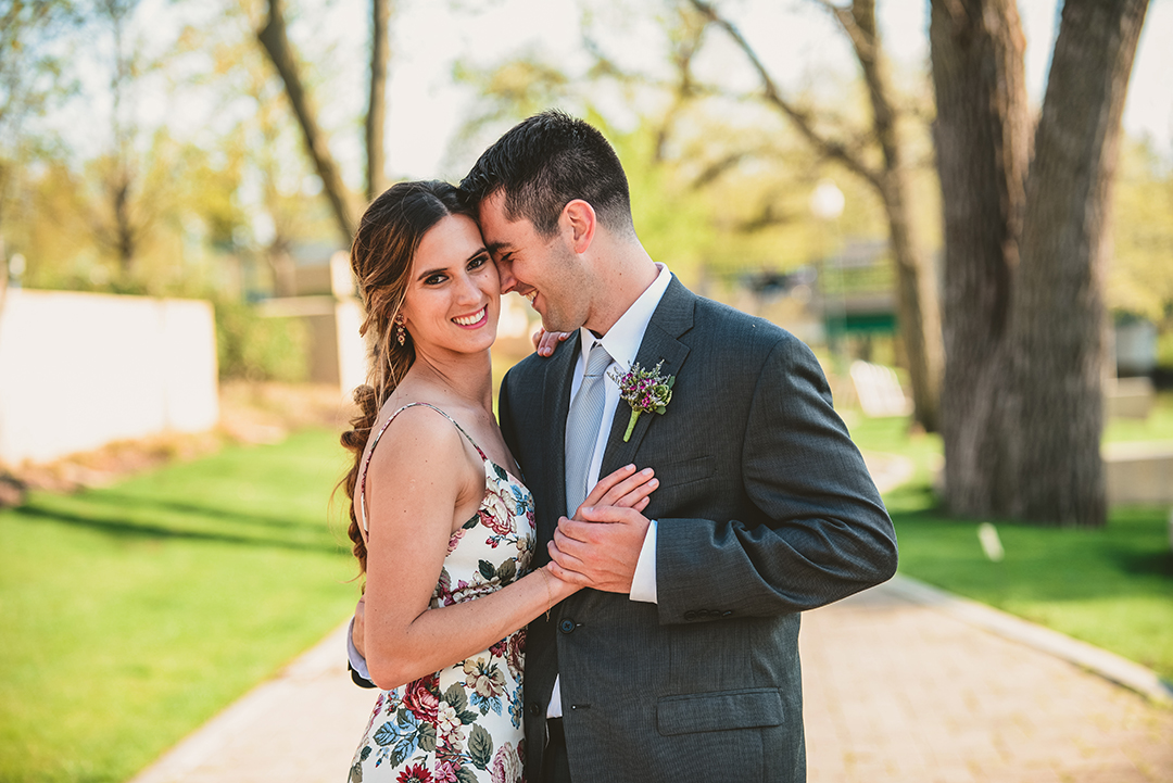 a groom snuggling up with his bride in the setting sun