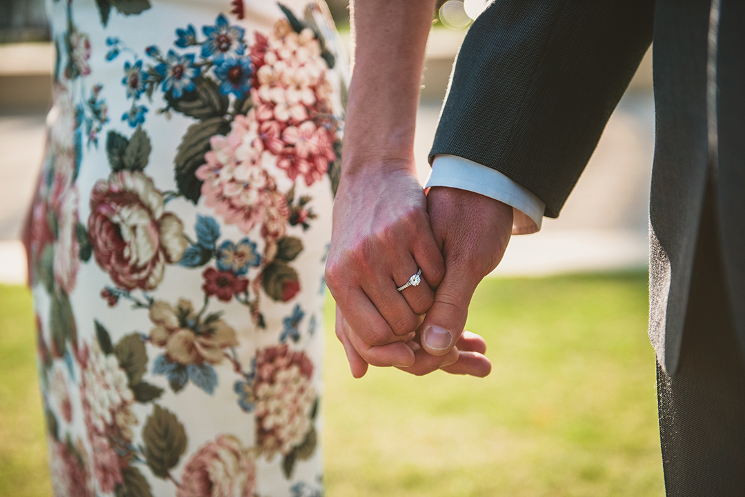 a wife holding her husbands hand with her beautiful ring sparkling