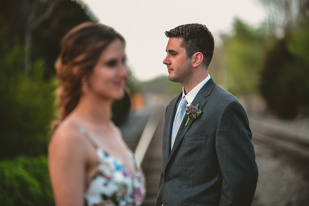 a serious groom in the distance with his bride in the foreground