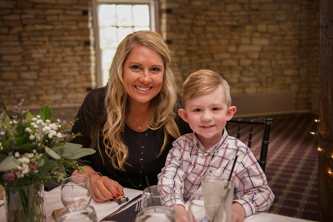 a young boy smiling as he sits with his mother at a Chicago wedding reception