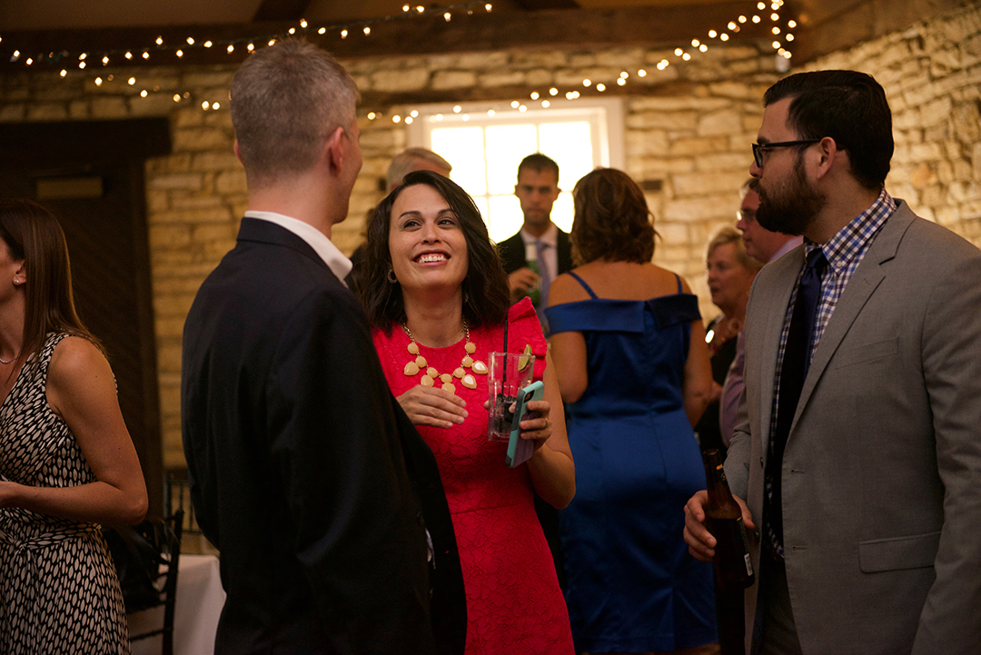 a woman wearing a red dress laughing as she speaks with her friends at a Chicago elopement