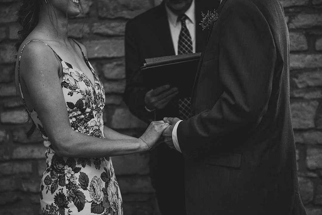 a bride and groom holding hands during their wedding ceremony at the Public Landing