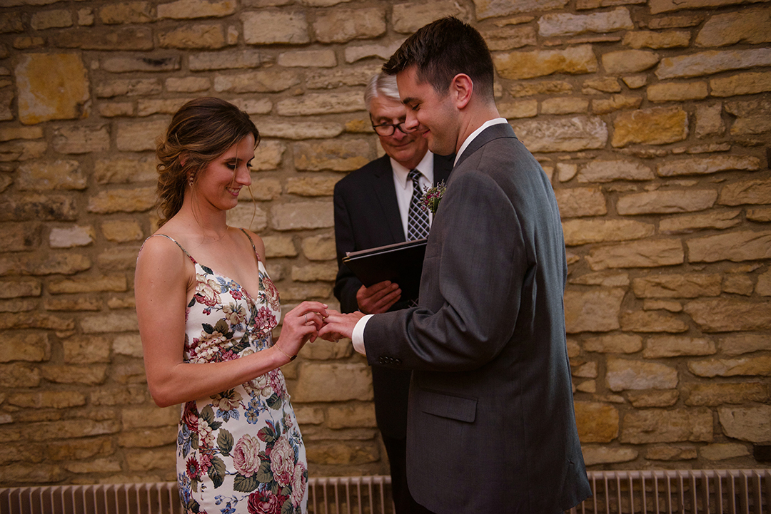 a bride placing a ring on her groom finger in Chicago