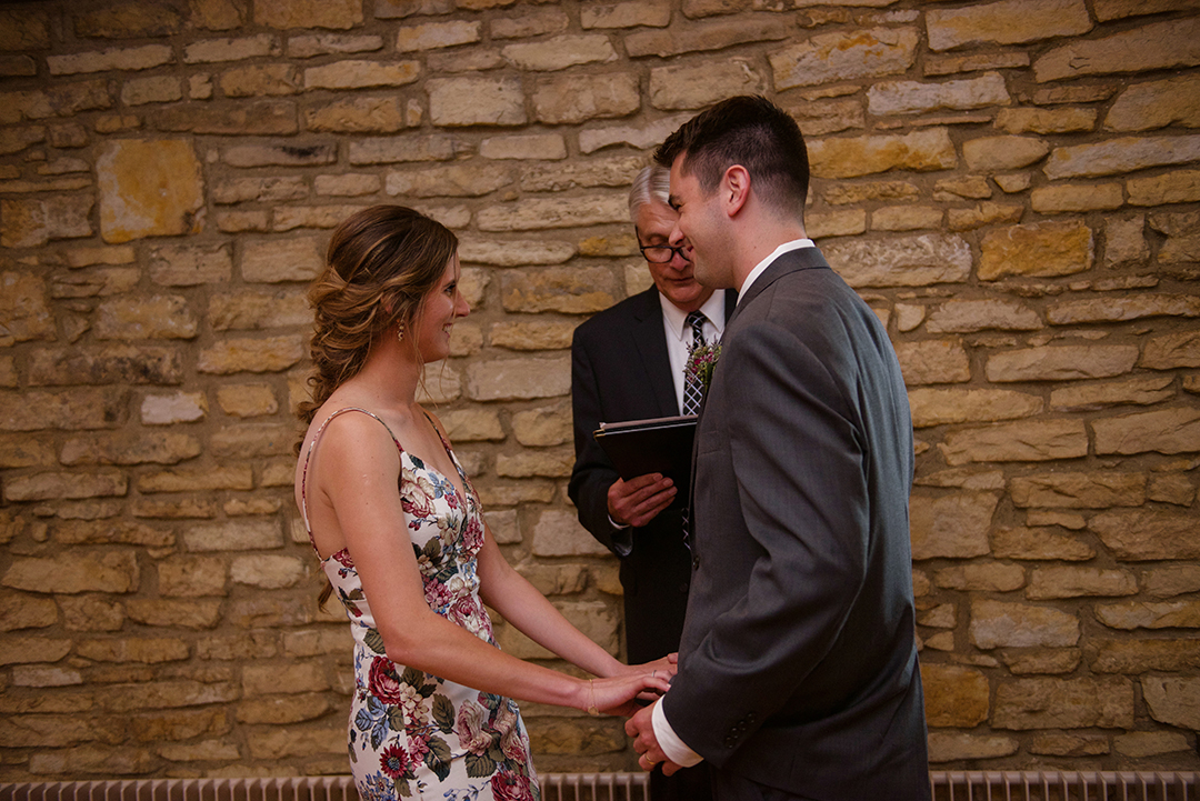 a bride and groom holding hands during their wedding ceremony at the Public Landing