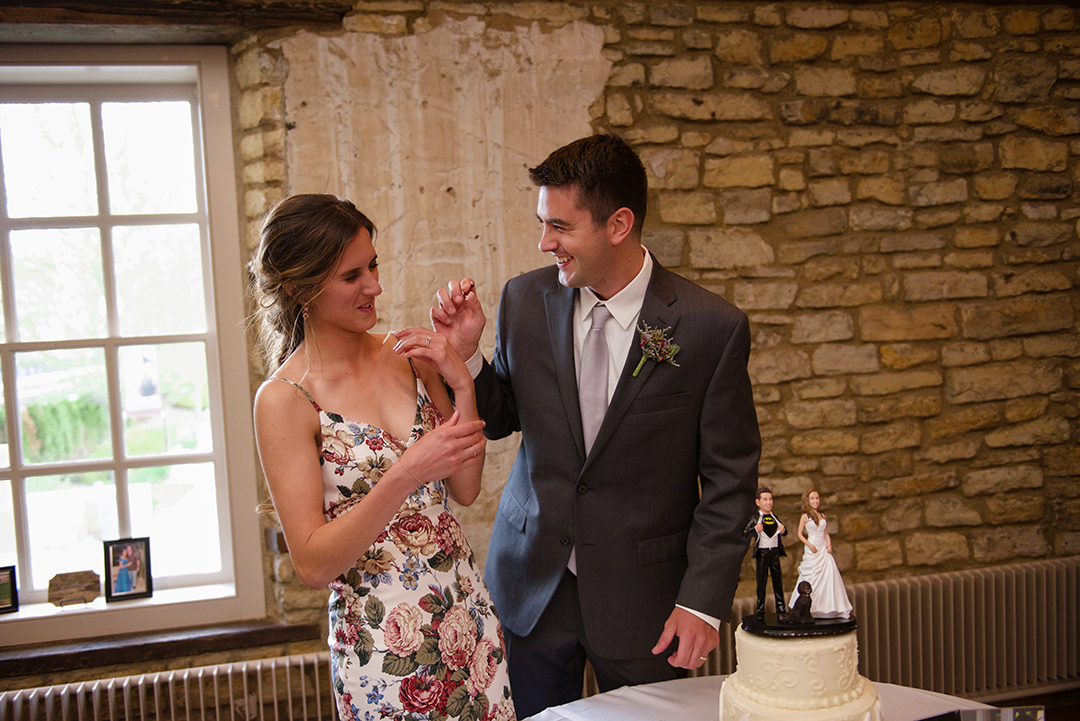 a wedding couple laughing as they feed each other wedding cake