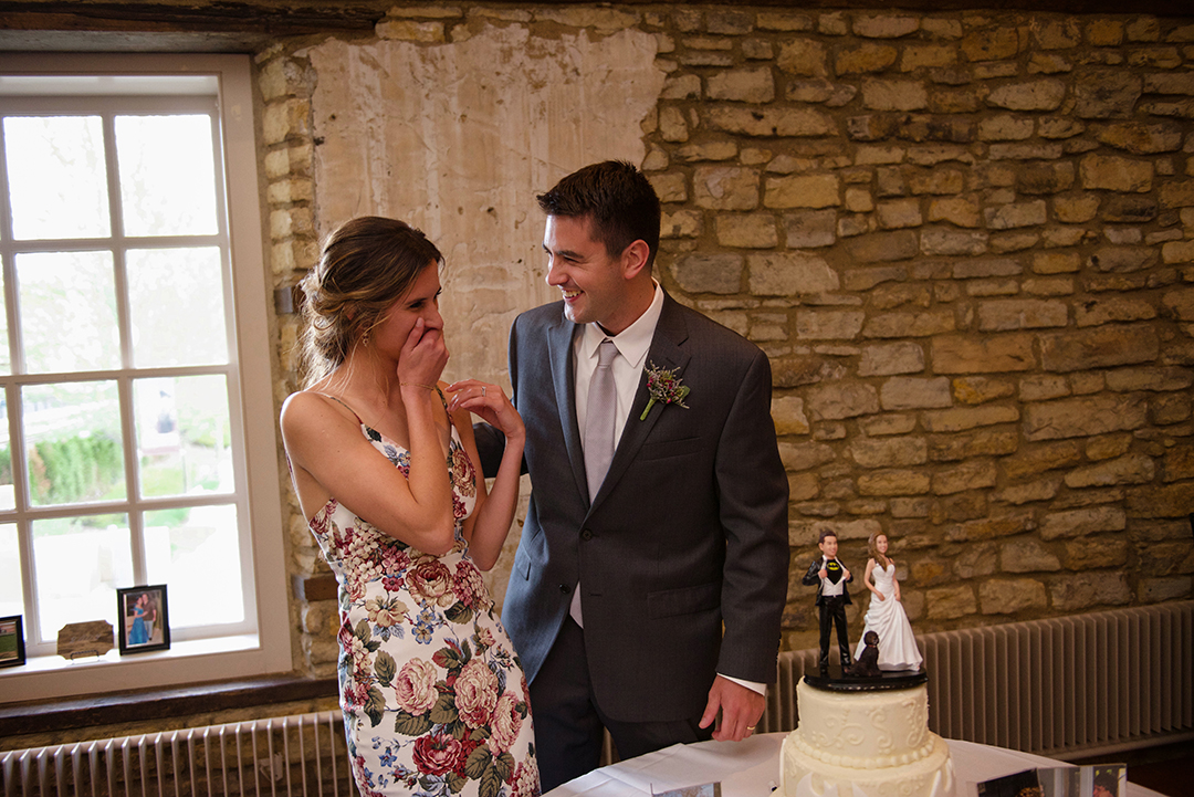 a bride laughing after her husband feeds her cake