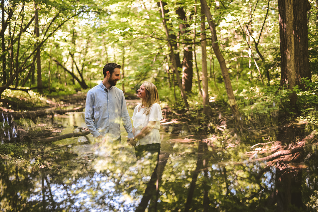 a creative image of a couple in the woods holding hands with a reflection