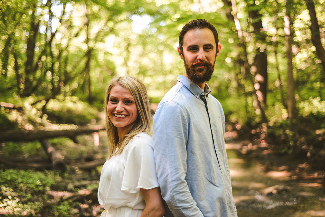 a man and a woman back to back in the lush Hammel Woods