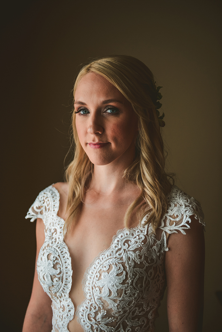 window light cascading across a beautiful bride as she looks at the camera with stunning blue eyes