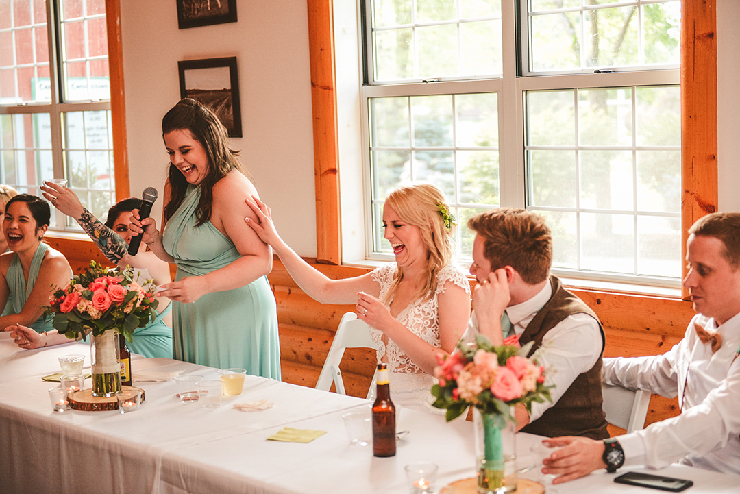 the bride laughing uncontrollably as the maid of honor gives her speech in a barn at the All Season Orchard