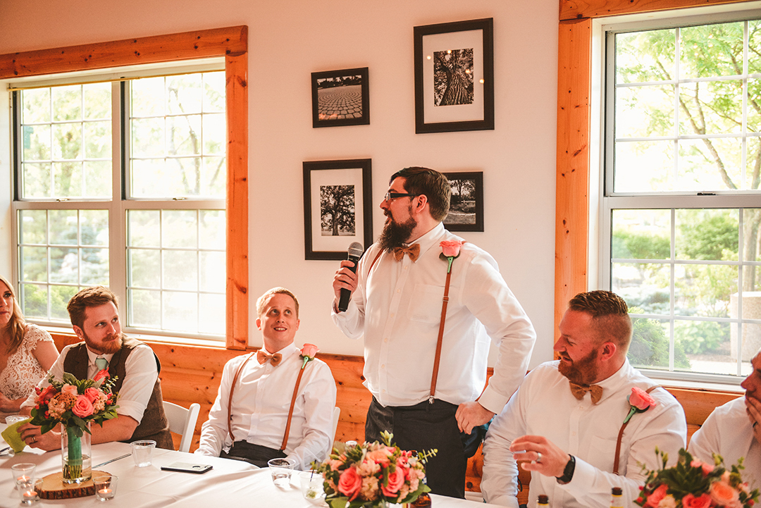 the best man giving a speech as the full bridal party watches with smiles on their faces