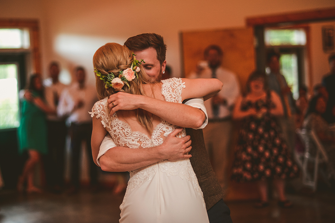 a husband hugging his bride as they dance during their first dance at the All Season Orchard in Woodstock