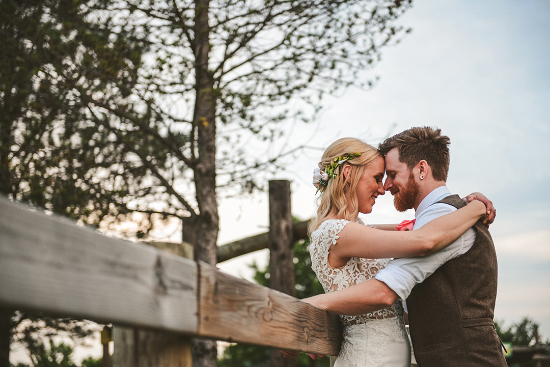 a husband and wife touching heads while they smile in the warm glow of the setting sun in Woodstock IL