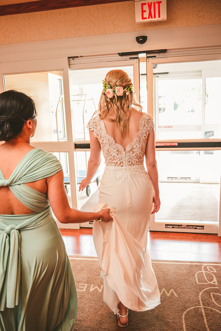 a bridesmaid holding the brides dress as they leave the hotel in Woodstock