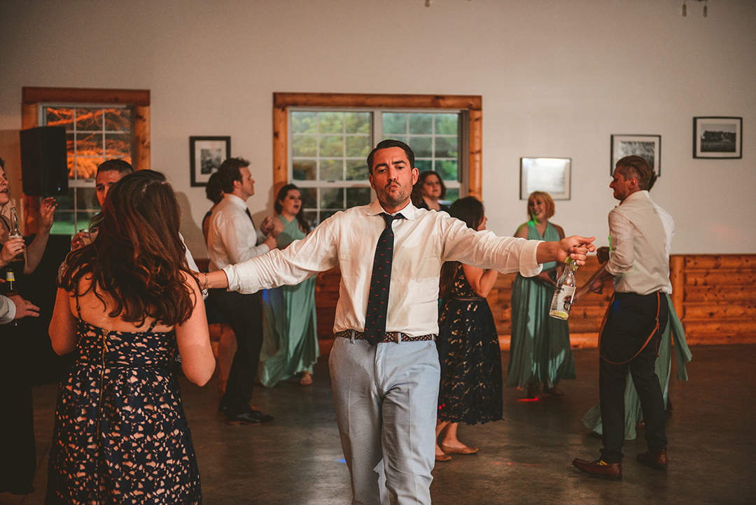 a man dancing with his girlfriend at a rustic farm wedding reception in Woodstock IL