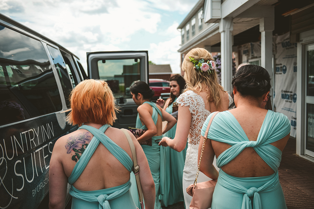 the bride and her bridesmaids climbing into a van with her girls in front of their hotel