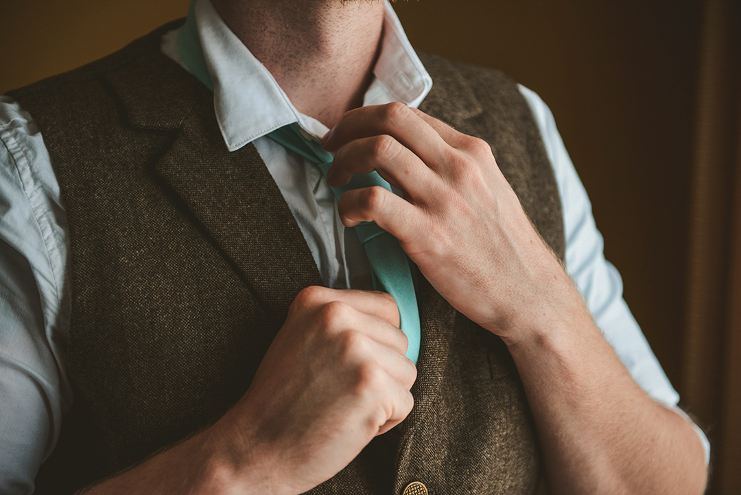 the groom fixing his tie moments before he leaves for the wedding in Woodstock IL