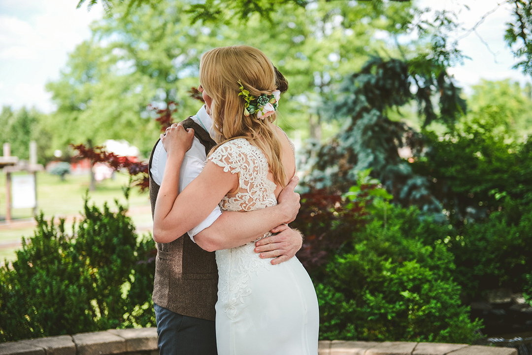 a bride hugging her husband during their first look at an apple orchard