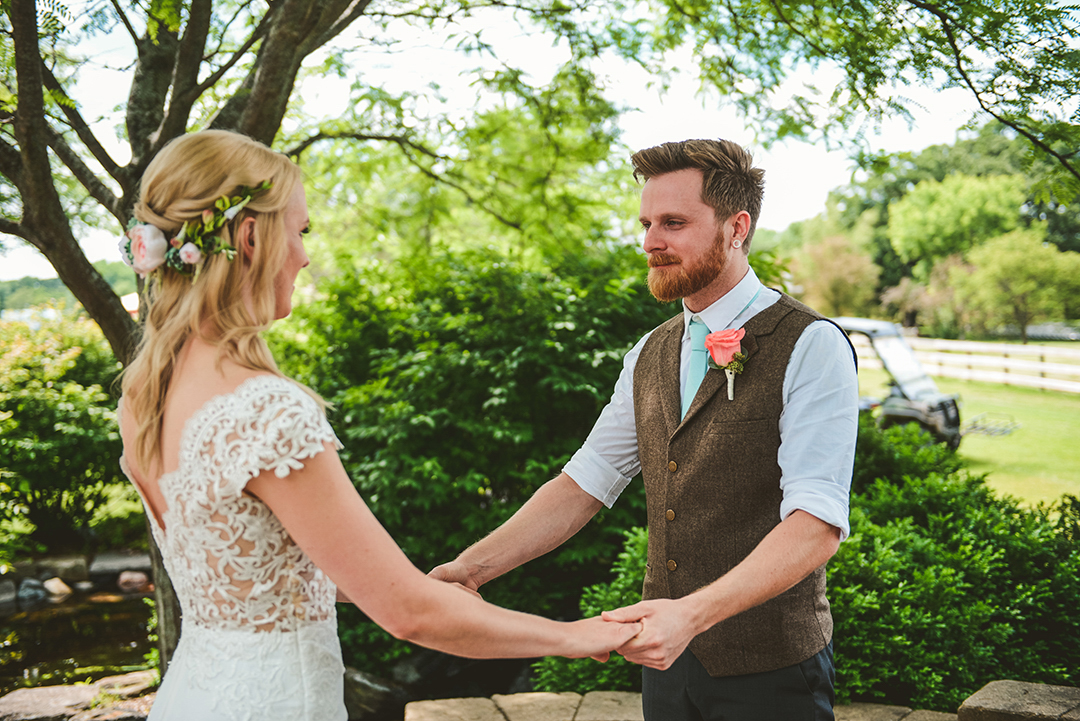 a man looking at his bride for the first time as they hold hands at an apple orchard wedding