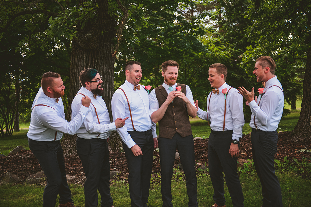 a group of groomsmen laughing as they give the groom a hard time at an apple orchard