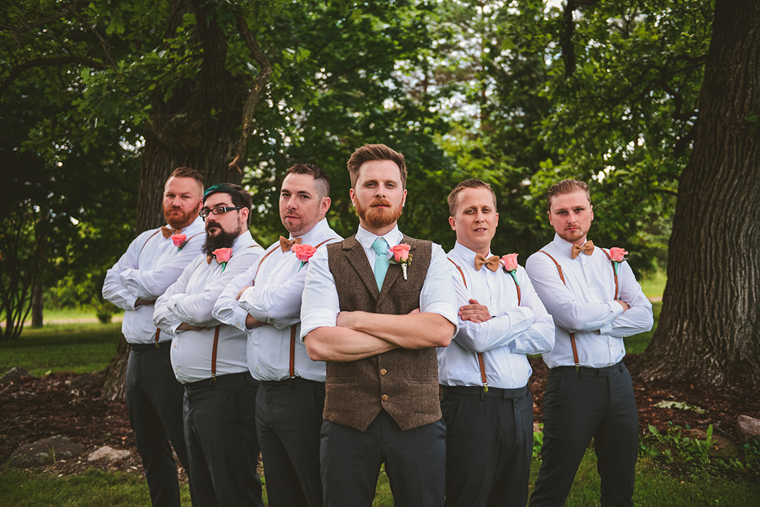 a group of groomsmen standing with their arms crossed in moody light at an apple orchard in Woodstock IL