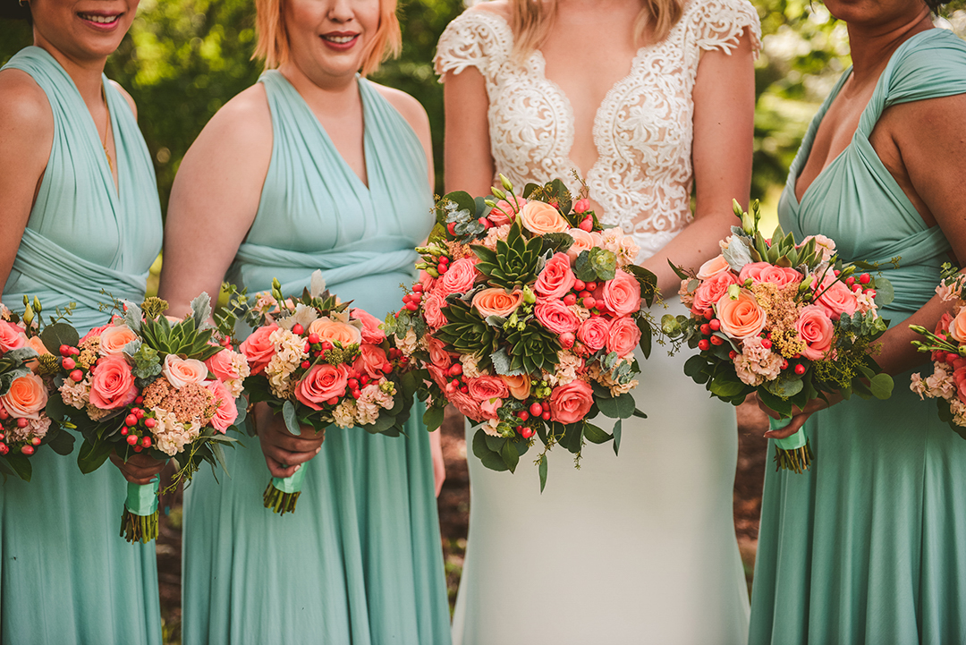 a detail of the girls holding their bouquets on a wedding day at an apple orchard