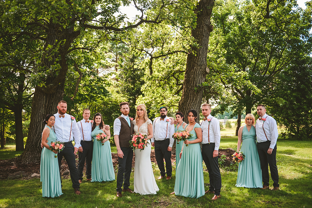 a moody image of a full bridal party standing in front of two old trees at the All Season Orchard in Woodstock IL