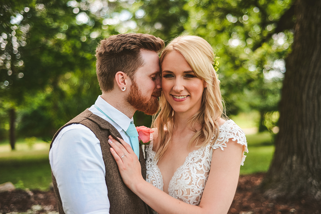 a groom kissing his brides cheek as she smiles in the golden light