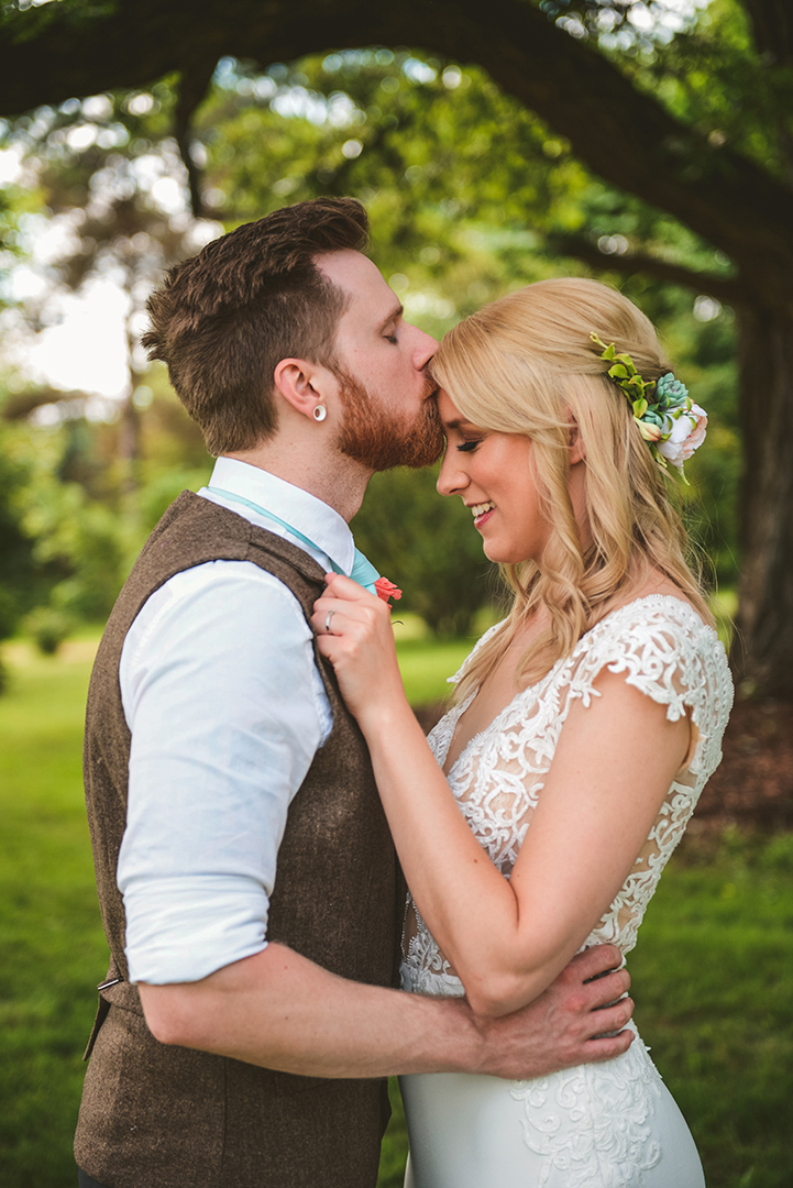 a groom kissing his brides head as she laughs at the All Season Orchard in Woodstock IL