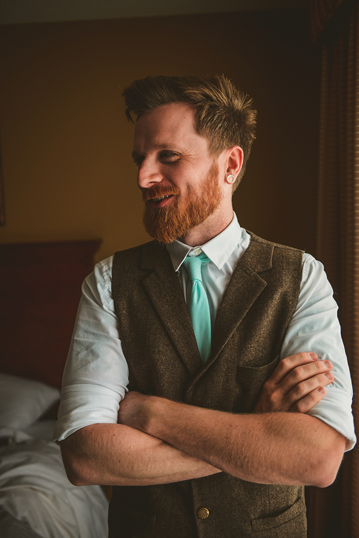 the groom standing with his arms crossed as he laughs at something a groomsman said in Woodstock IL