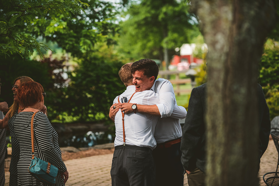 a wedding guest hugging a groomsmen at a wedding in Woodstock Il