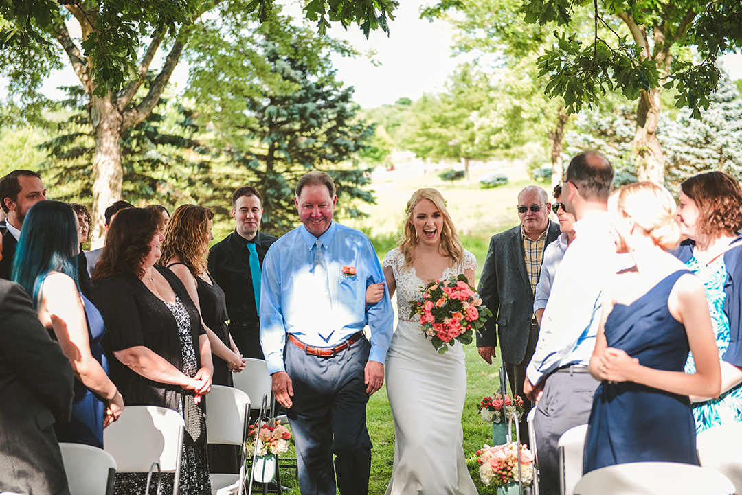 a bride laughing with excitement as her father walks her down the aisle of her closest friends and family in Woodstock IL