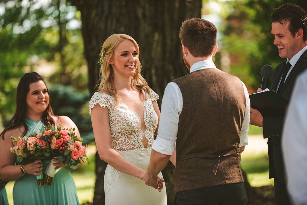 a bride laughing as she looks at her groom with her maid of honor laughing in the background