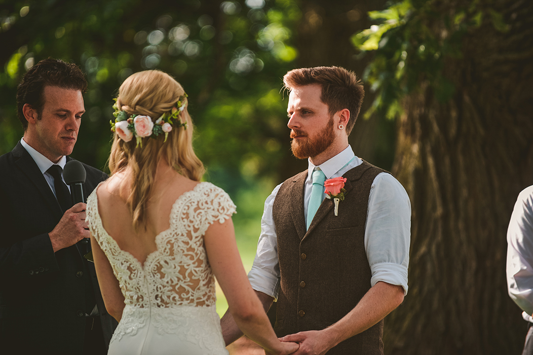 over the brides shoulder of a groom holding his wives hands during his wedding at the All Season Orchard in Woodstock