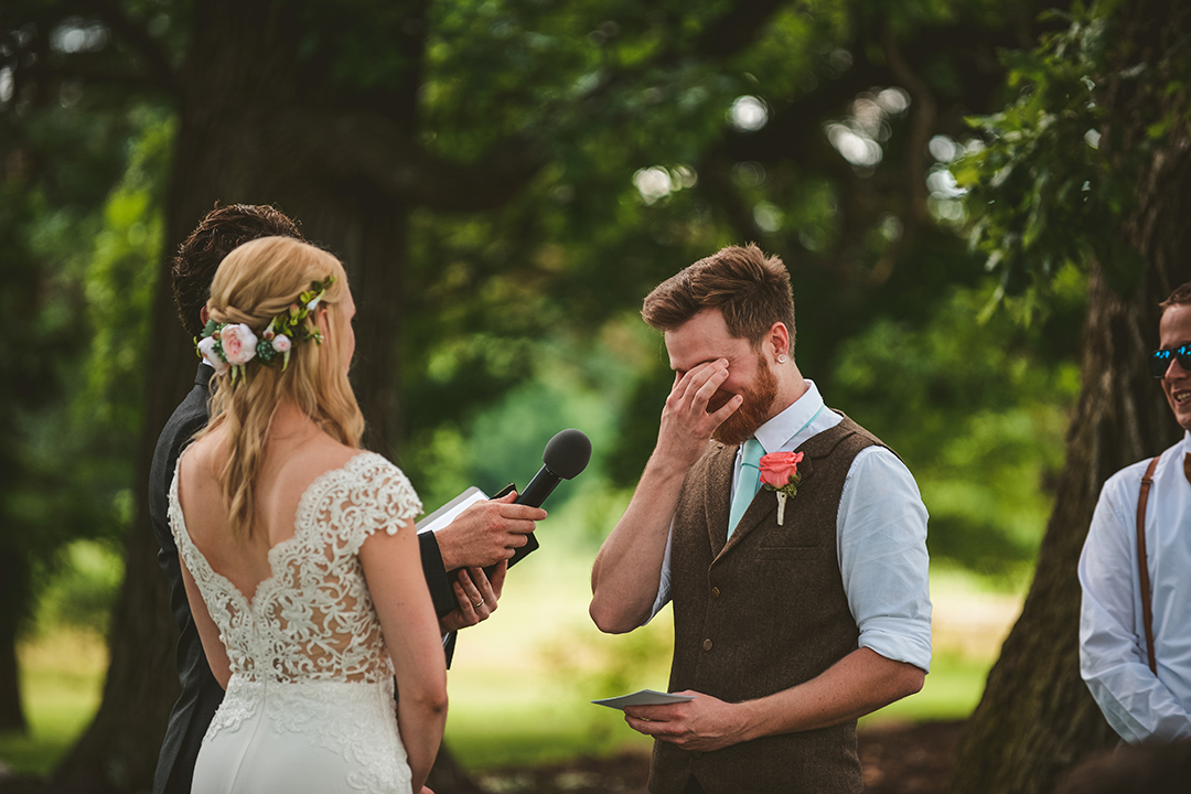 a groom crying and wiping away his tears as he says his vows to his bride and the All Season Orchard in Woodstock